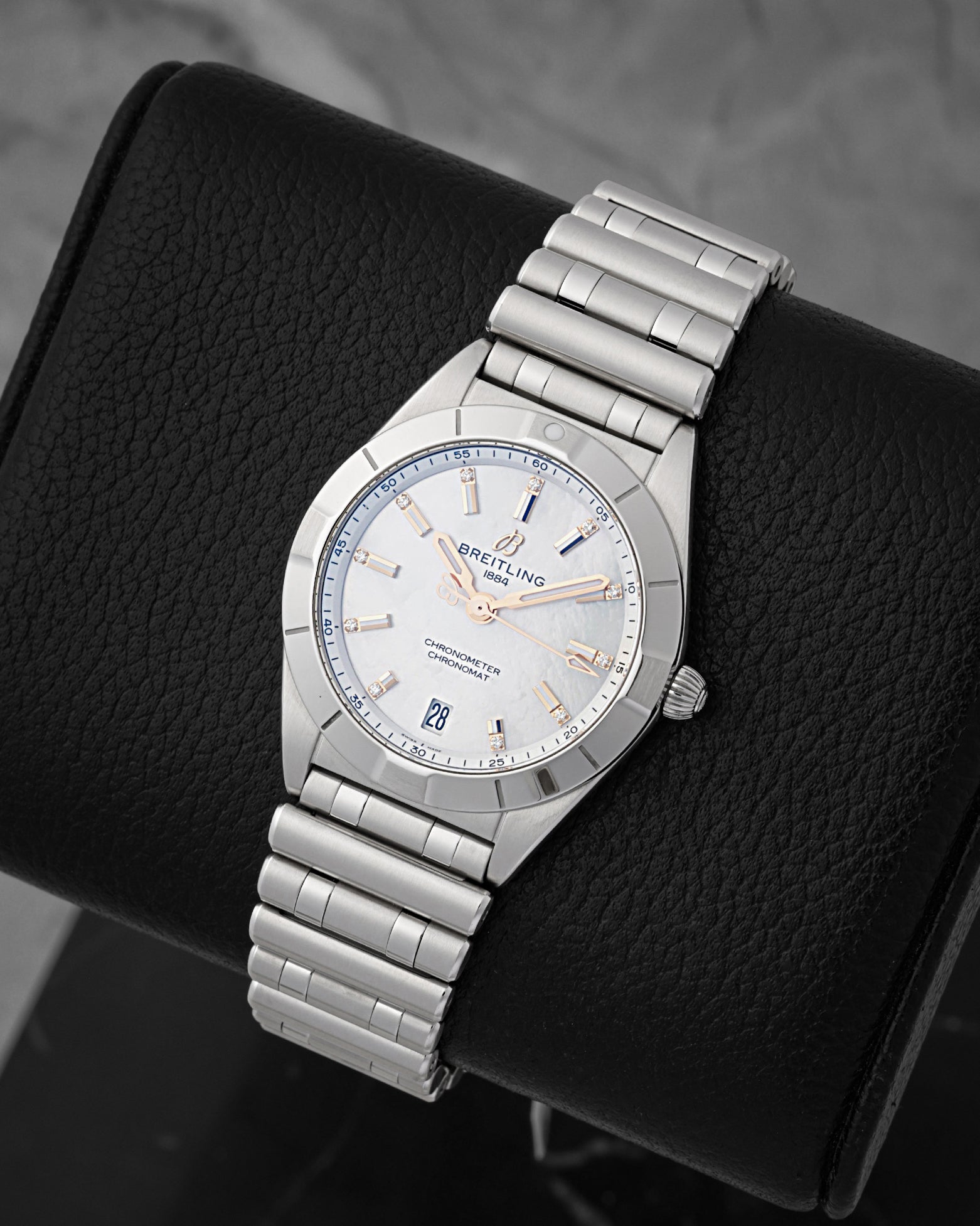A high-angle three-quarter portrait of the polished 32mm stainless steel watch case resting on a black leather display cushion to highlight its integrated case profile