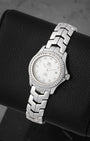 A high-angle three-quarter portrait of the polished 27mm stainless steel watch case resting on a black leather display cushion to emphasize the brilliant-cut diamonds