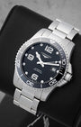 An angled studio profile shot of the stainless steel case and link bracelet of a black Longines HydroConquest automatic watch