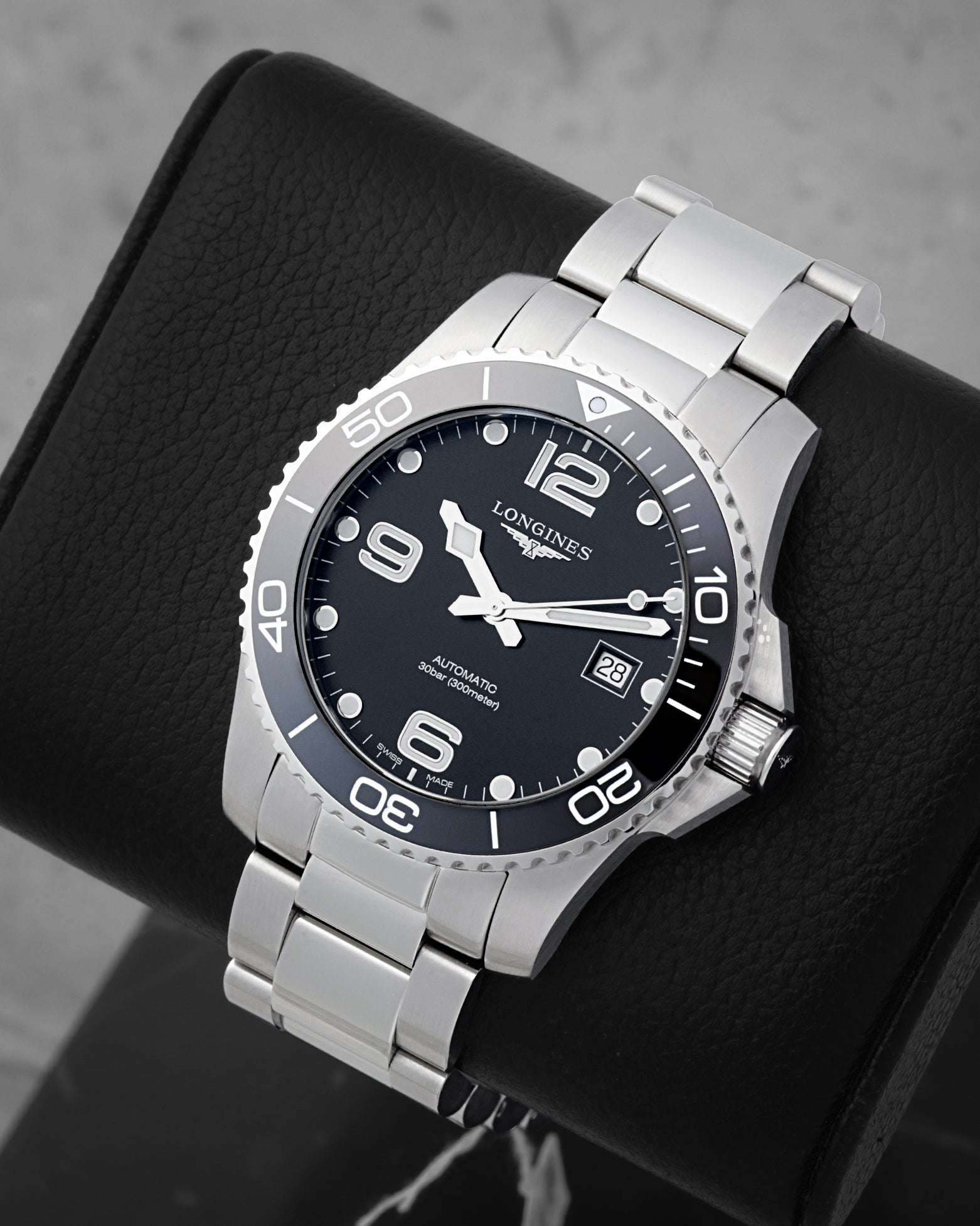An angled studio profile shot of the stainless steel case and link bracelet of a black Longines HydroConquest automatic watch