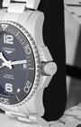 Side profile view of the stainless steel case showing the ceramic coin-edge bezel, heavy crown guards and signed screw-down crown