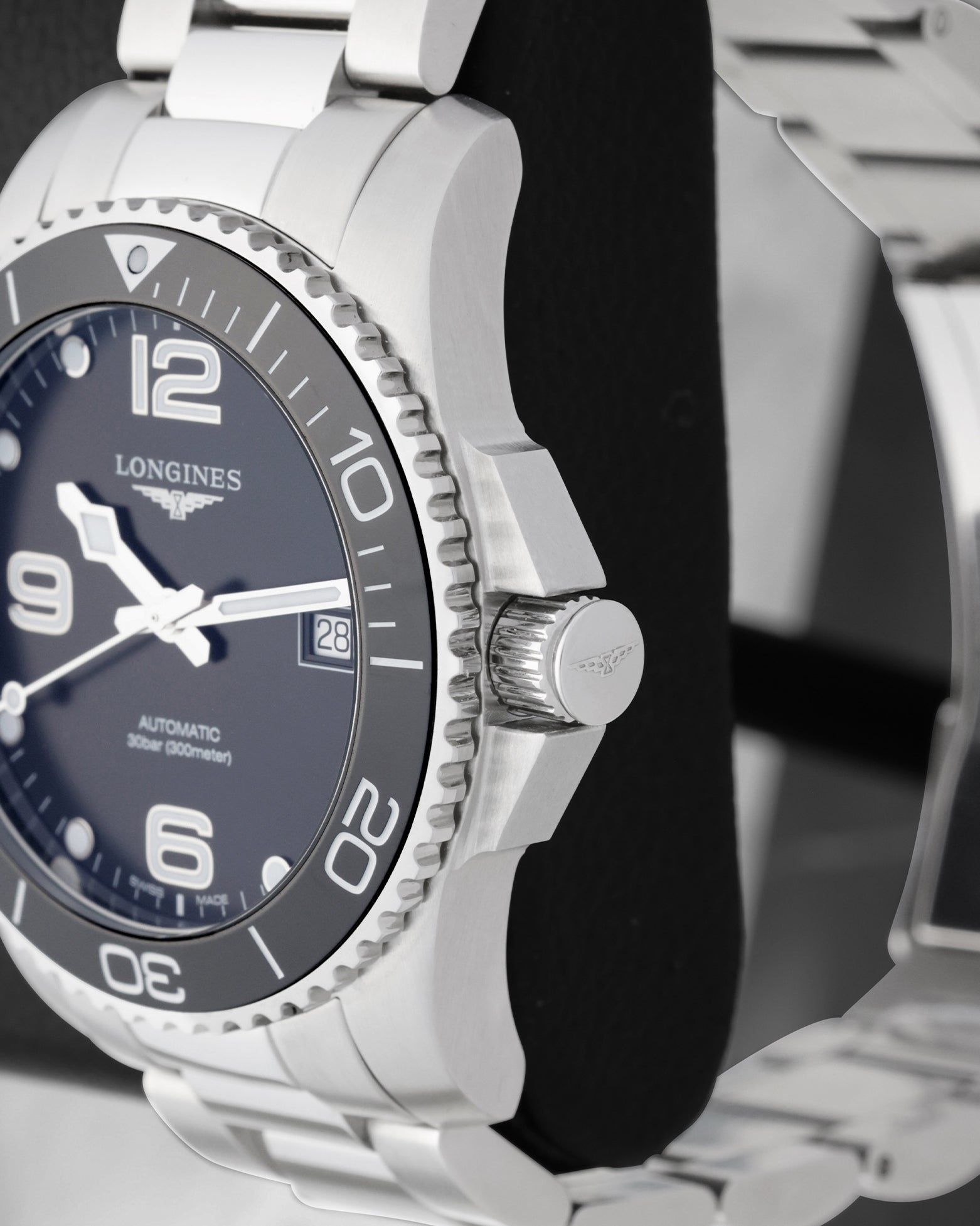 Side profile view of the stainless steel case showing the ceramic coin-edge bezel, heavy crown guards and signed screw-down crown