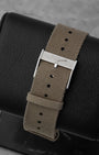 Close-up of the khaki green NATO-style fabric strap and stainless steel pin buckle on a Longines watch