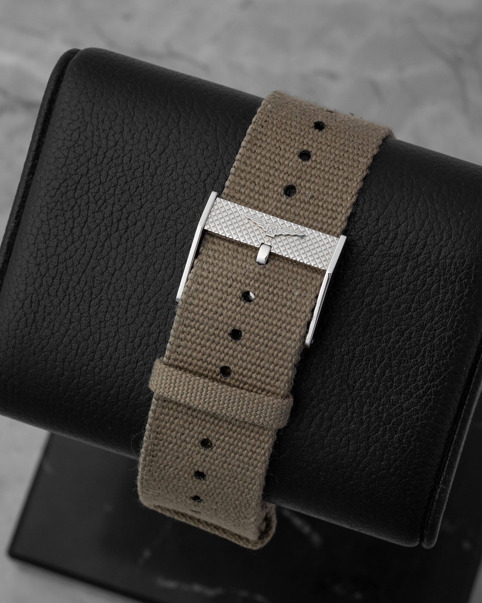 Close-up of the khaki green NATO-style fabric strap and stainless steel pin buckle on a Longines watch