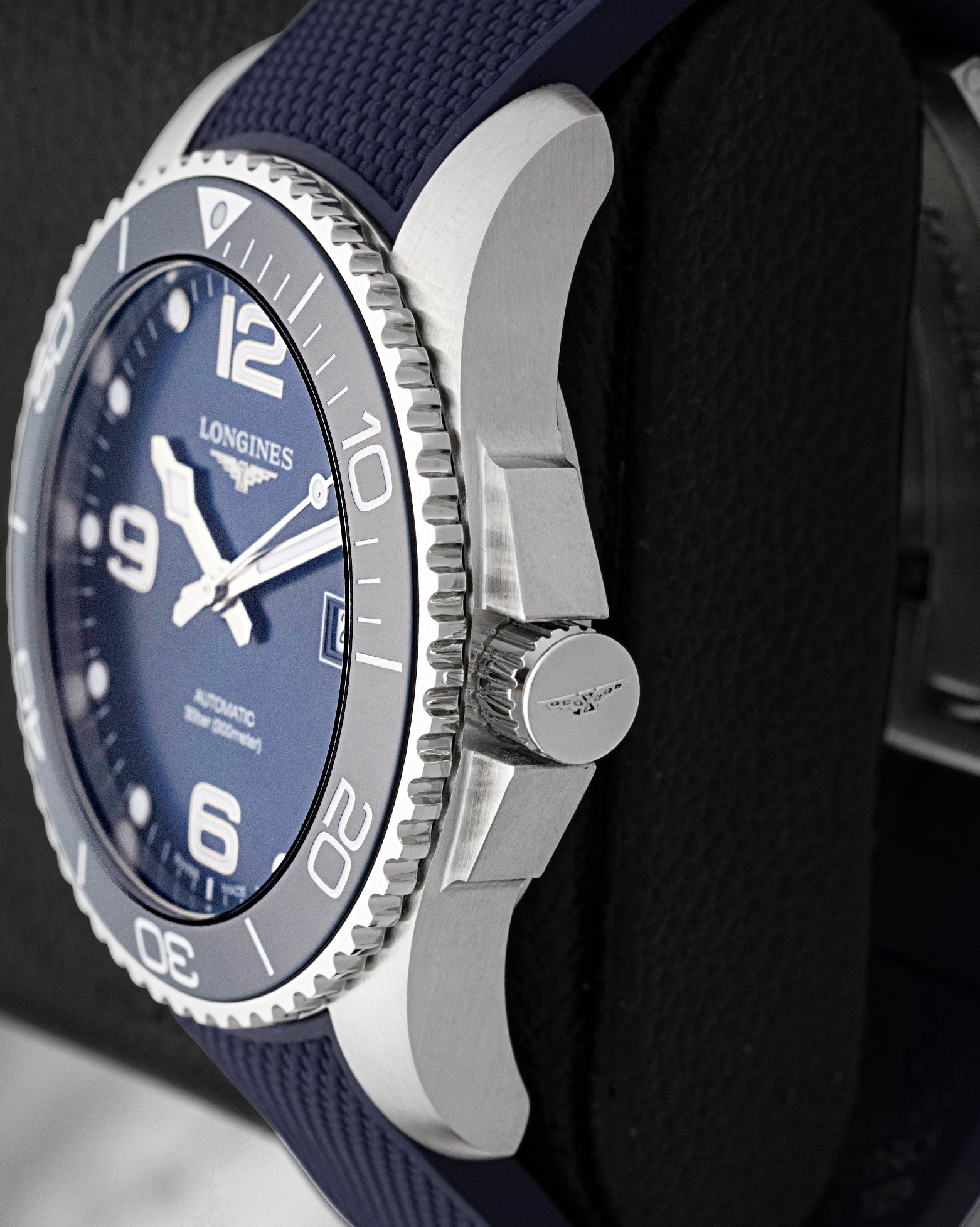 Side profile view showing the protective crown guards, screw-down winding crown, and stainless steel case on blue Longines HydroConquest L3.781.4.96.9