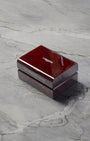 A closed rectangular high-gloss cherry wood finish Longines luxury watch presentation box sitting centered on a grey marble background