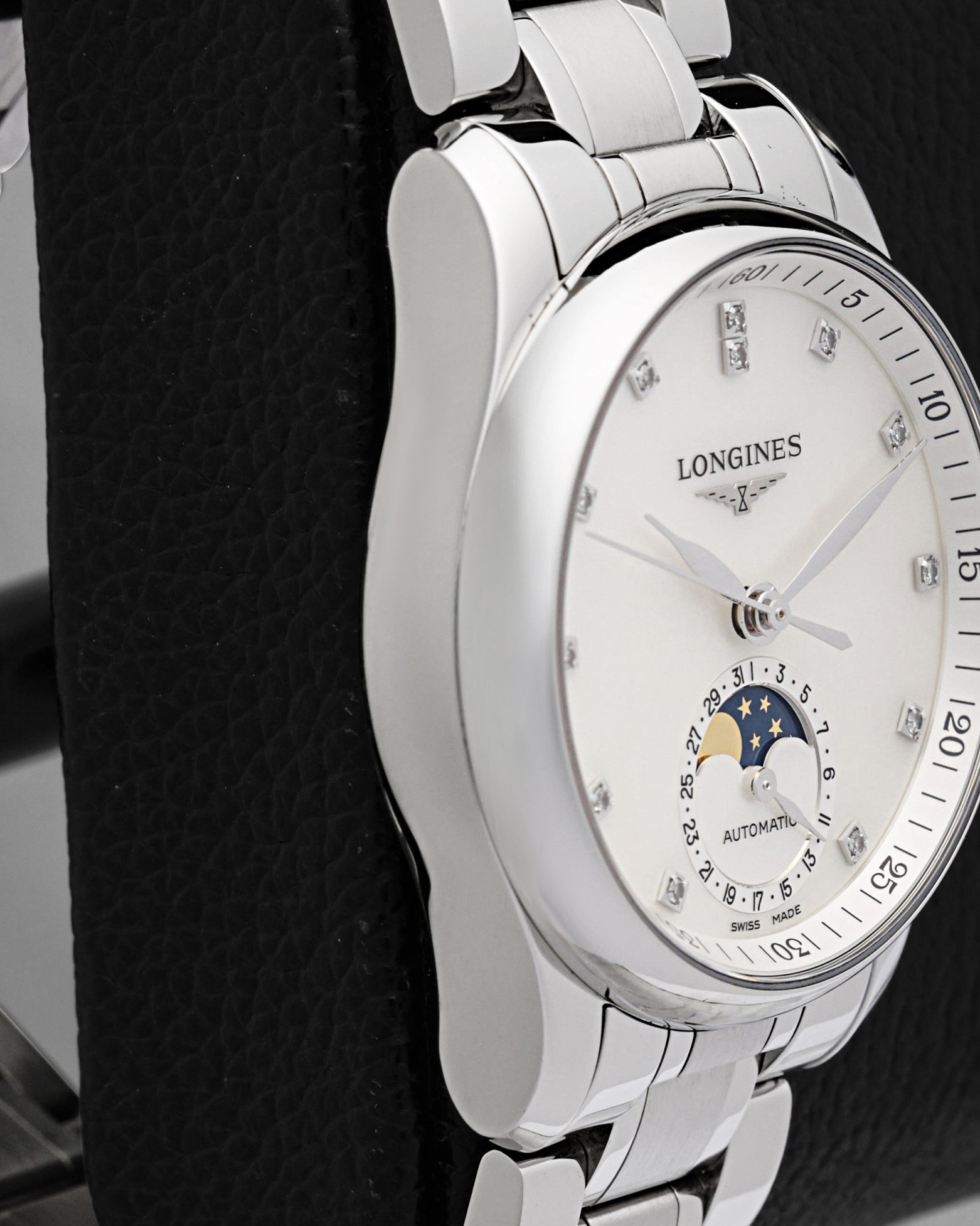 Left-side macro profile view showcasing the mirror-polished curved case flank and the ergonomic integration into the elegant H-link stainless steel dress bracelet