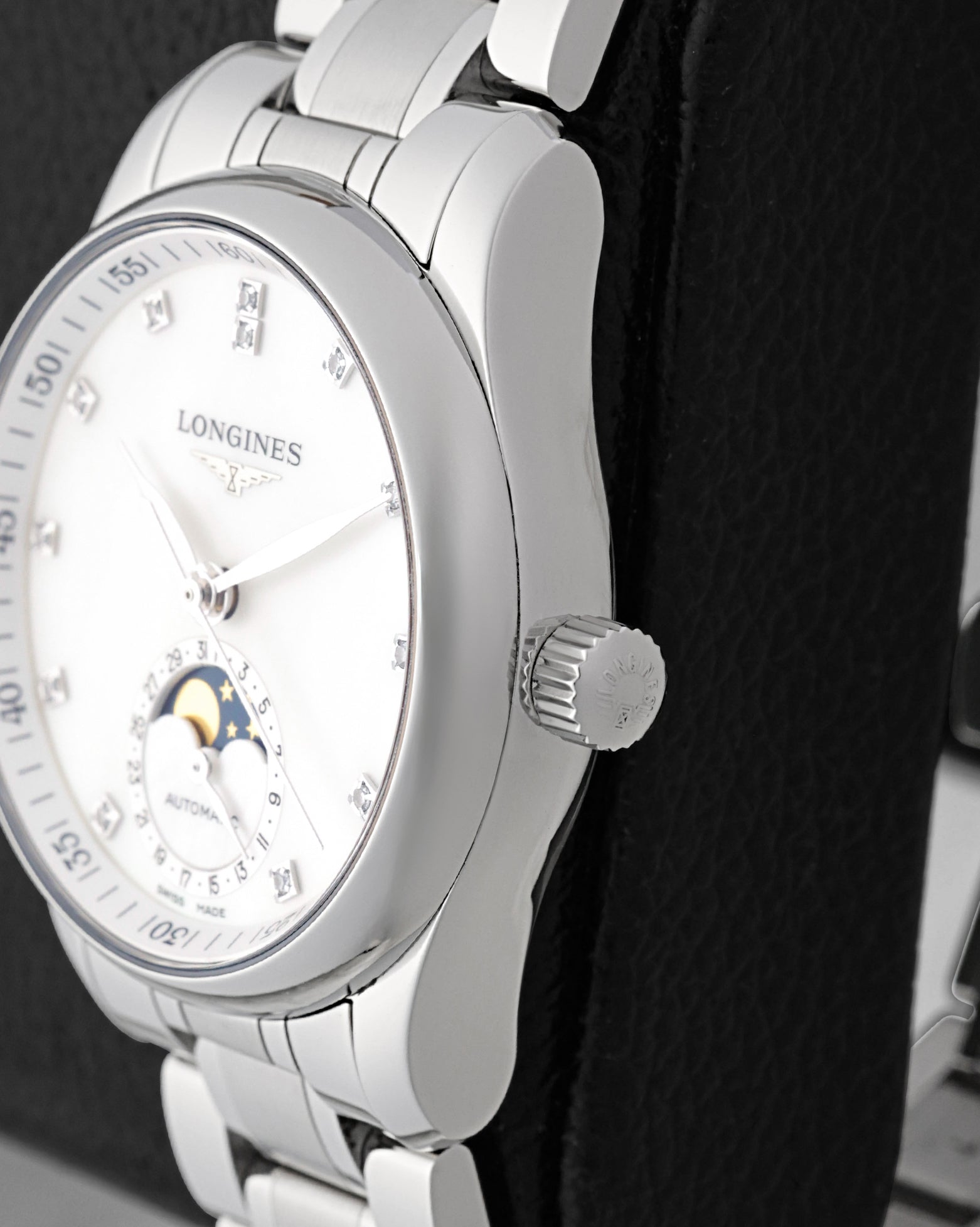 Close-up right profile view of the slim steel watch head focusing on the high-polished bezel edge and the textured push-pull winding crown signed with the winged hourglass crest