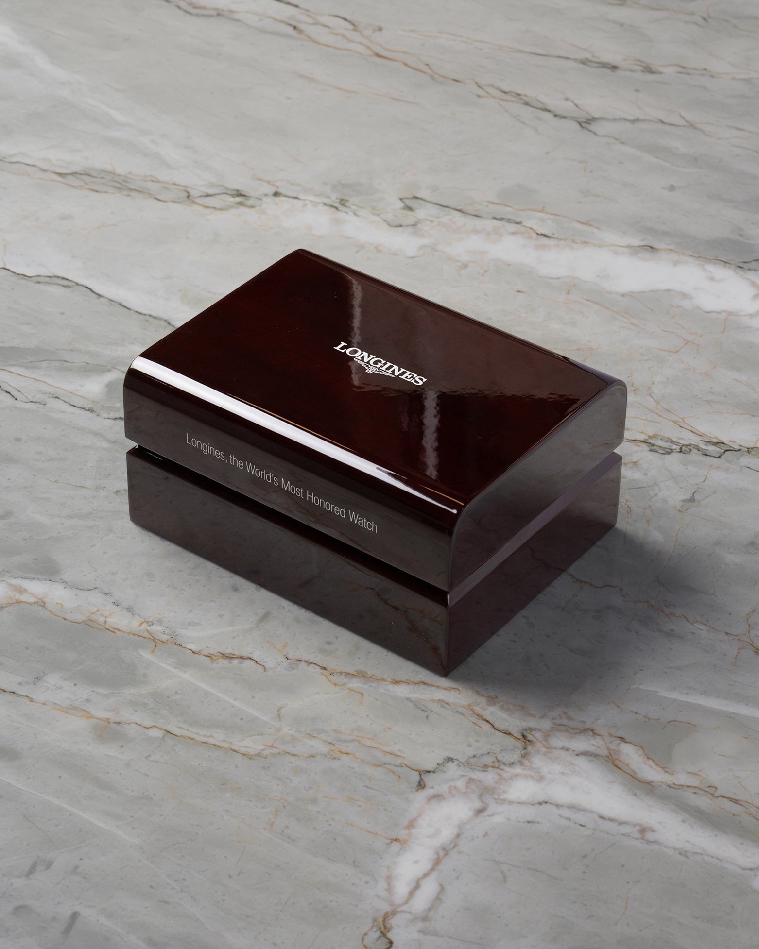 A high-angle three-quarter shot of the official premium dark mahogany wood grain watch presentation chest detailed with a high-gloss lacquer finish