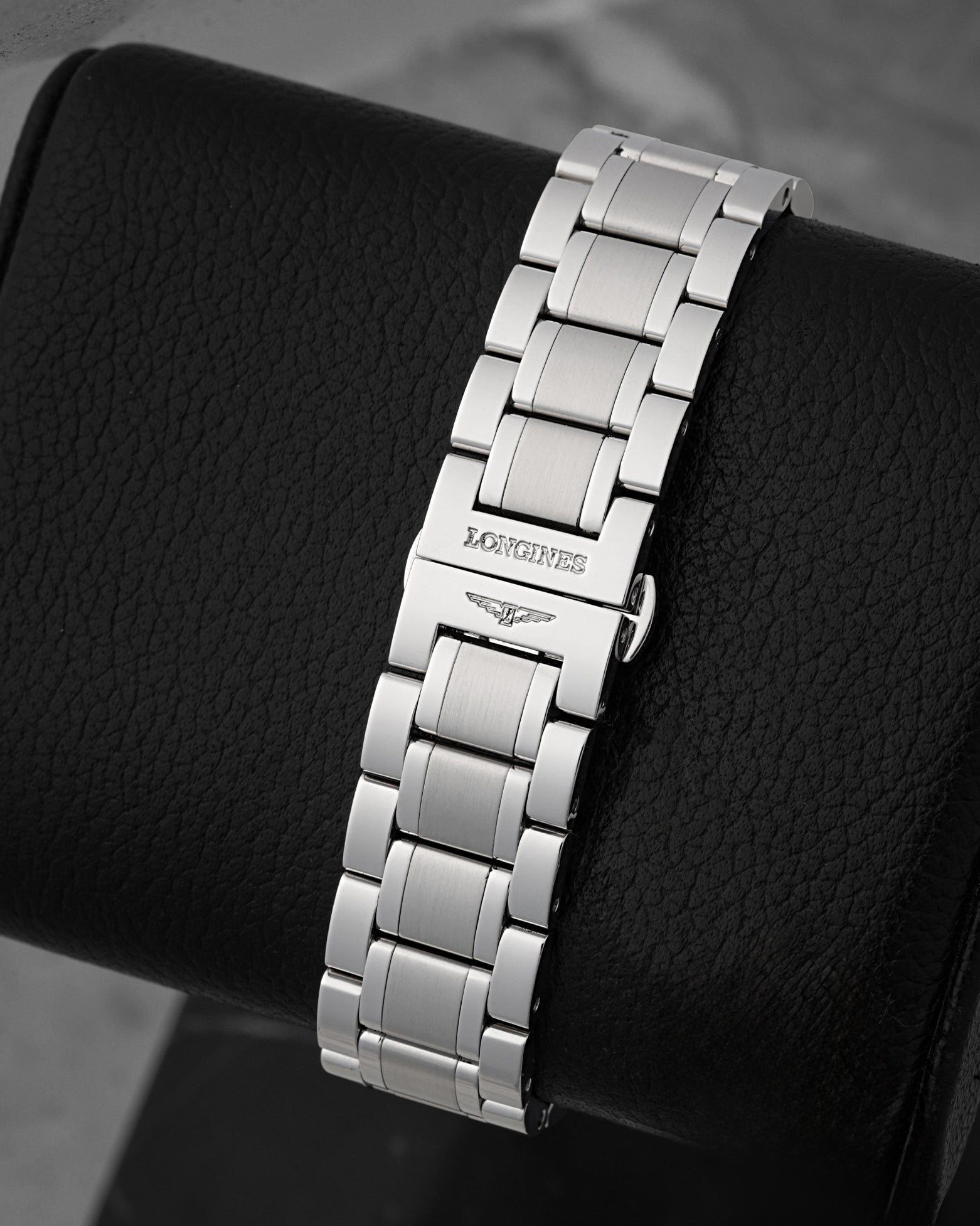 A rear portrait of the high-polished and brushed steel bracelet focusing on the seamless closure of the hidden butterfly push-button deployment buckle stamped with the Longines logo