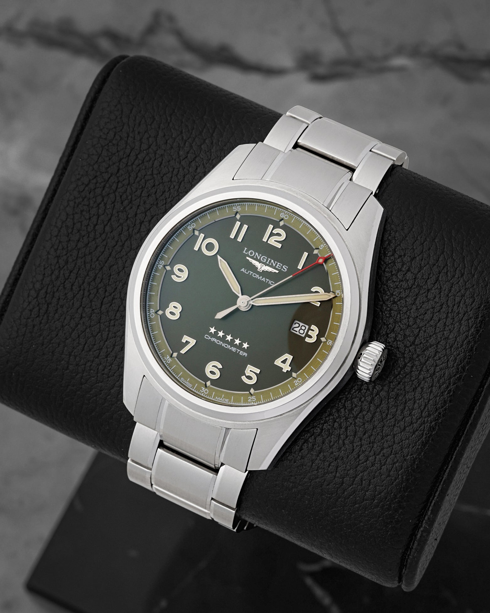 A high-angle three-quarter studio view of the stainless steel Longines Spirit case showcasing its raised sapphire crystal, stepped bezel, and red-tipped sweeping seconds hand