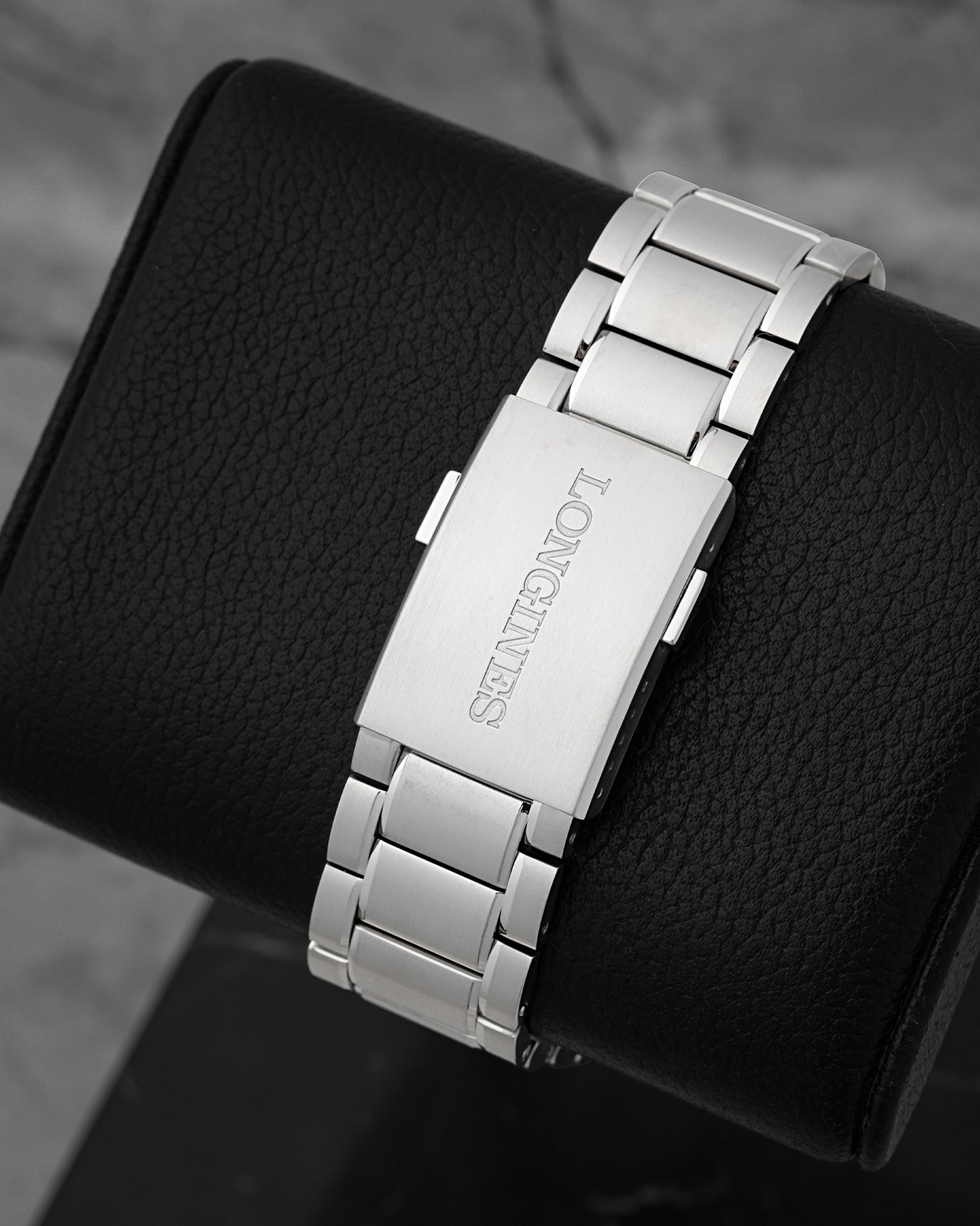 A rear view of the satin-finished three-link steel bracelet focusing on the flush interface of the folding deployment buckle engraved with the classic Longines block typography