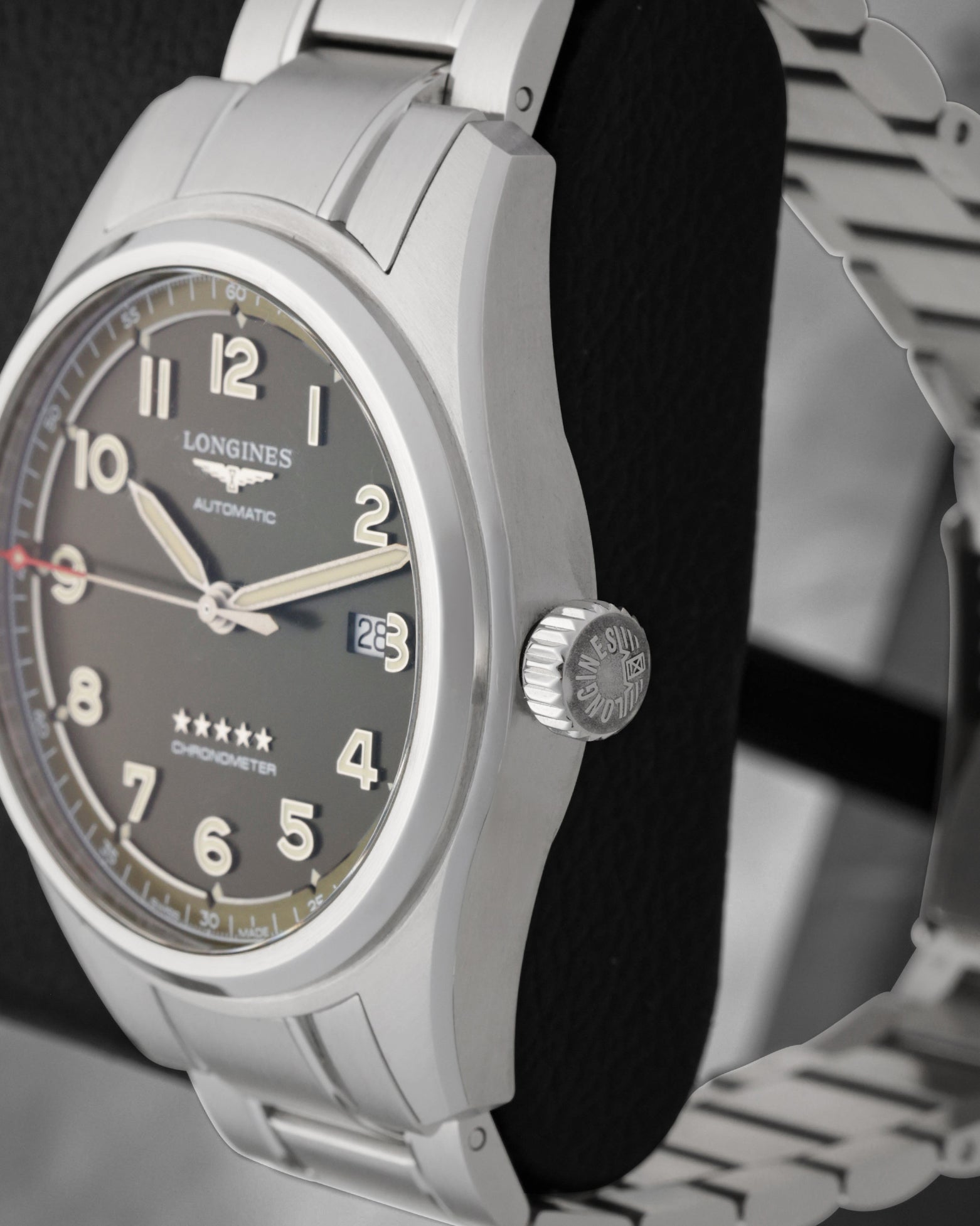 Close up right profile view of the watch head highlighting the large vintage-style fluted winding crown embossed with the Longines winged hourglass logo emblem