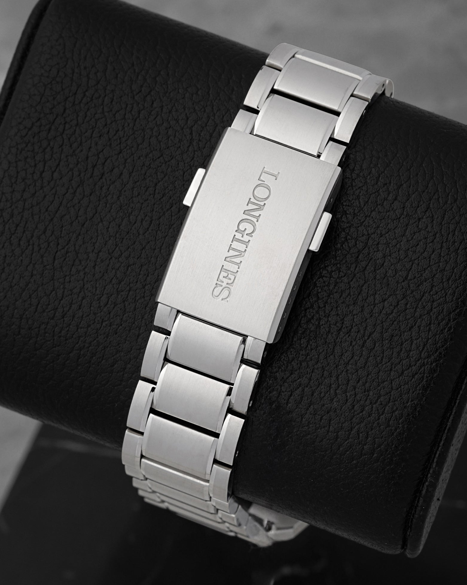 A rear view of the satin-finished three-link steel bracelet focusing on the flush interface of the folding deployment buckle engraved with the classic Longines block typography
