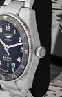Close-up right profile view of the watch head highlighting the knurled ceramic bezel edge and the large fluted screw-down winding crown engraved with the winged hourglass crest
