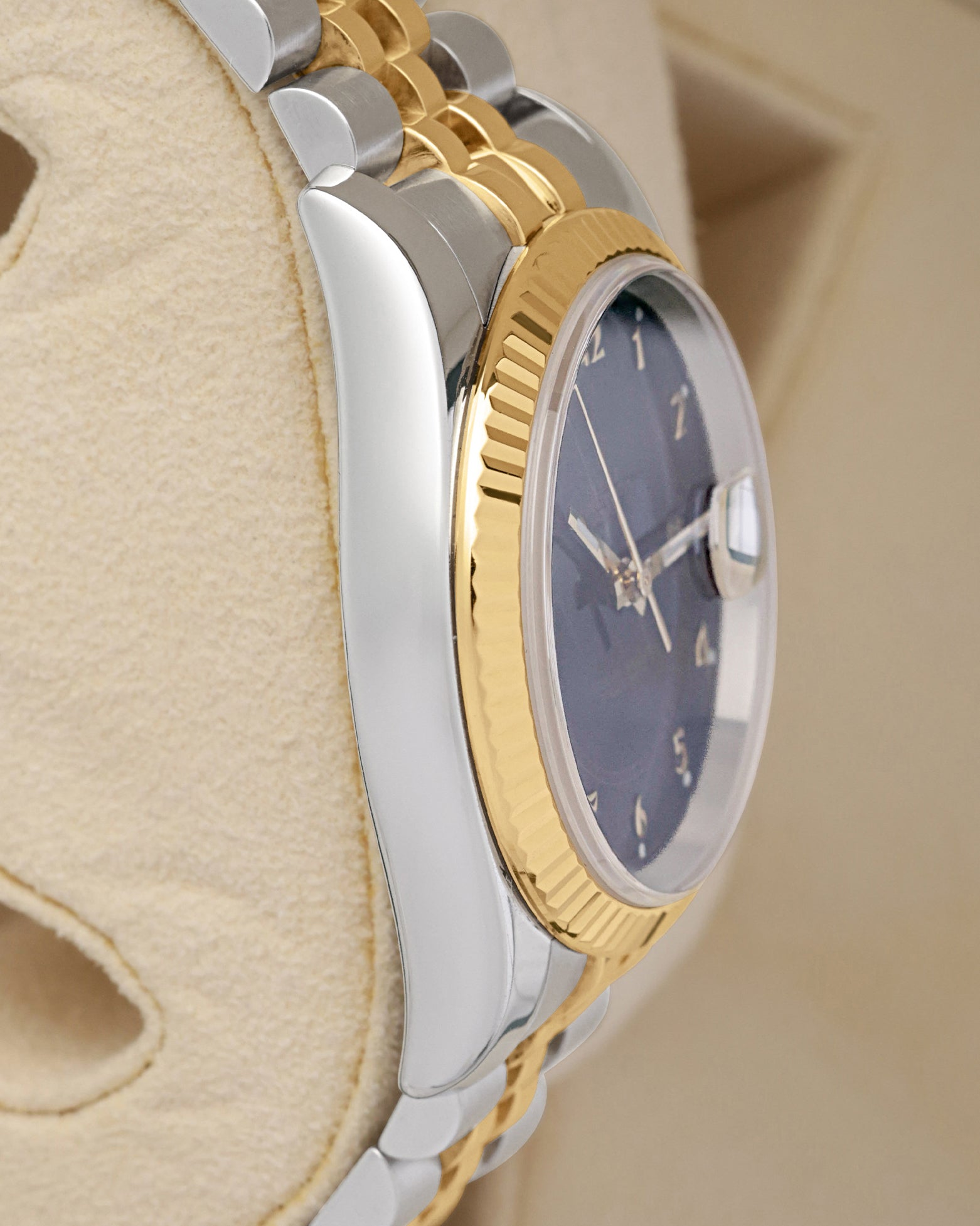 Left side perspective showcasing the polished steel case side profile and the distinct texture of the 18k gold fluted dress bezel