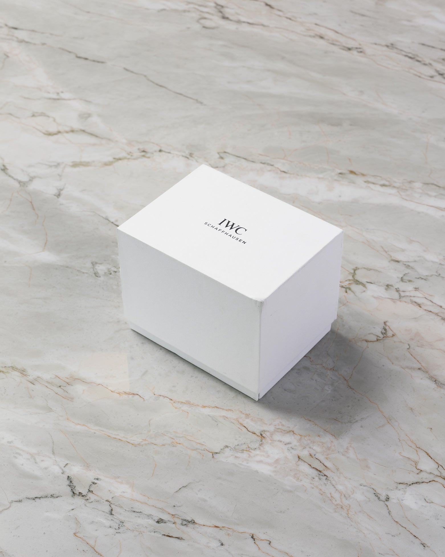 Official minimalist white IWC Schaffhausen outer watch packaging box resting on a marble surface