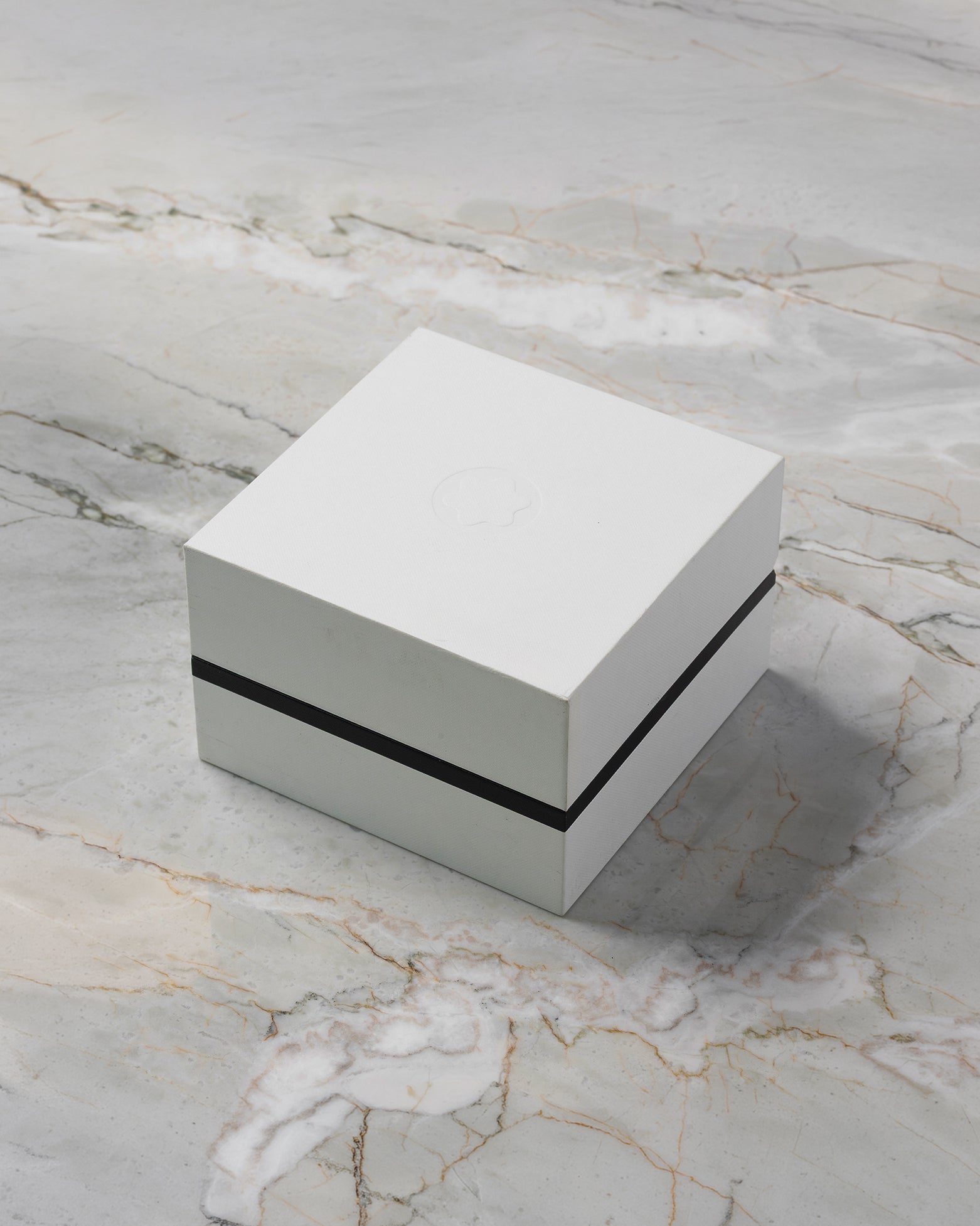 A high-angle three-quarter shot of the official minimalist square grey and black Montblanc watch presentation box resting closed on a marble backdrop