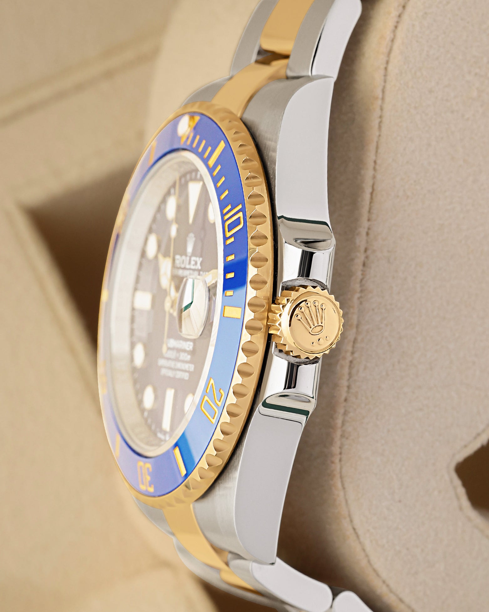 Right side profile view highlighting the 18k yellow gold winding crown and blue Cerachrom ceramic bezel on a Rolex Submariner Bluesy