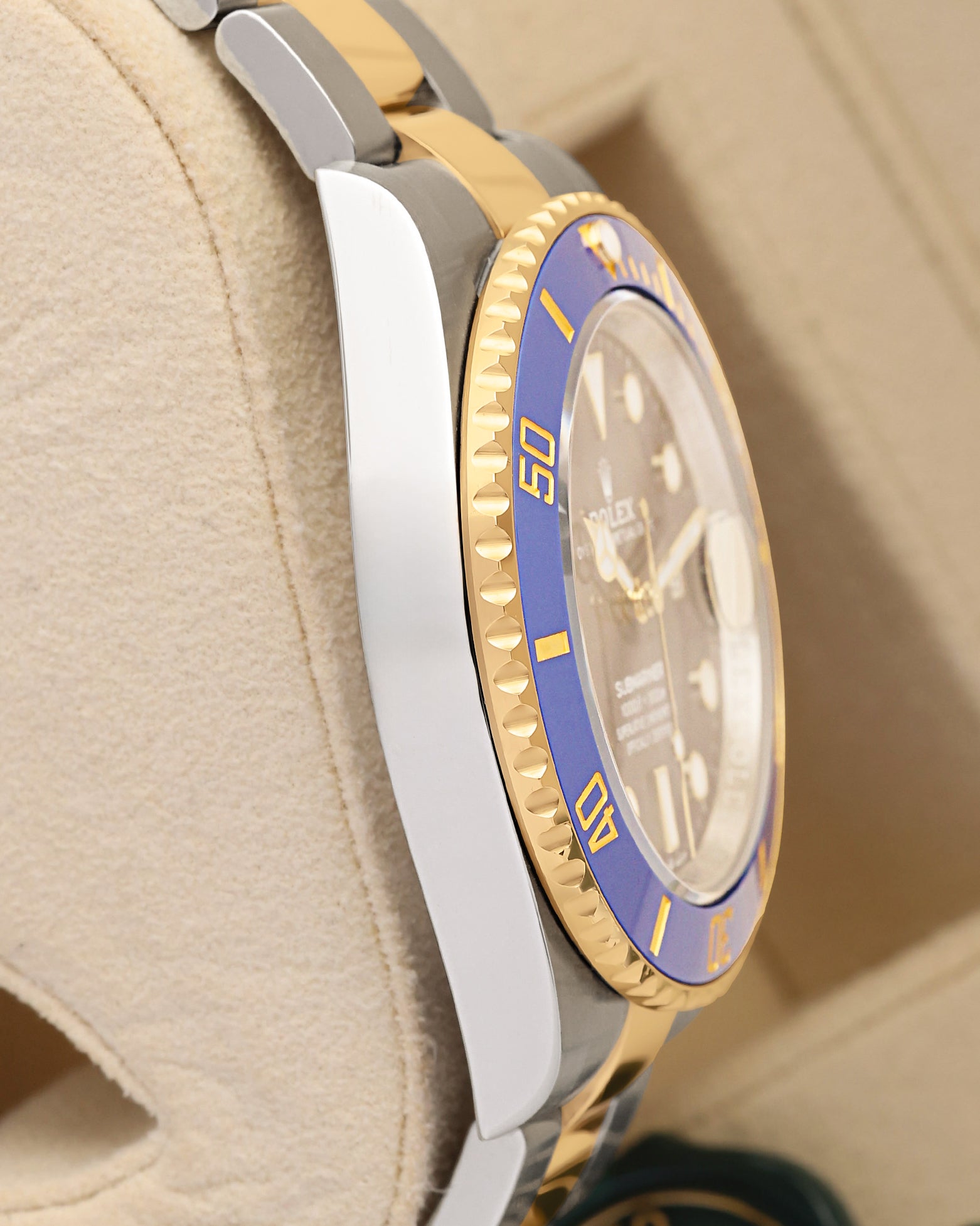 Left side view showcasing the polished Oystersteel case edges and distinct knurled gold bezel profile of the 41mm Rolex Bluesy