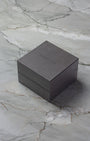 Original square textured brown TAG Heuer luxury watch presentation box displayed on a premium white marble surface