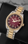 A high-angle three-quarter studio profile of the 38mm symmetrical two-tone watch case resting on a black leather cushion to emphasize the deep gradient effect of the red dial