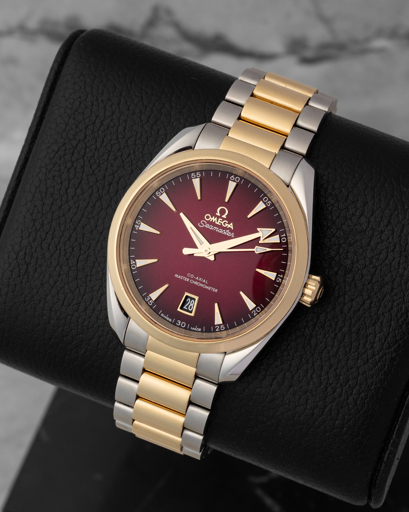 A high-angle three-quarter studio profile of the 38mm symmetrical two-tone watch case resting on a black leather cushion to emphasize the deep gradient effect of the red dial