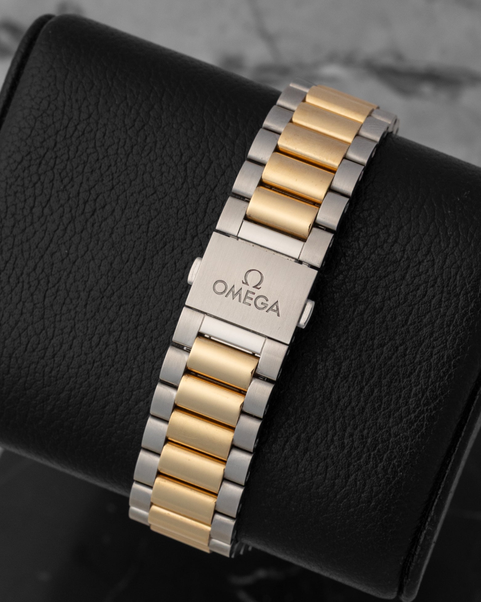 A rear view of the integrated bracelet with 18k gold center links and steel external links, focusing on the seamless closure of the hidden butterfly deployment buckle