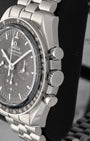 Close-up right profile view of the watch head highlighting the polished piston chronograph pushers flanking the fluted winding crown embossed with the Omega logo