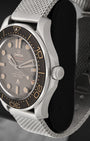 Side profile shot focusing on the brushed titanium case structure, knurled screw-down crown, and scalloped edges of the brown unidirectional bezel