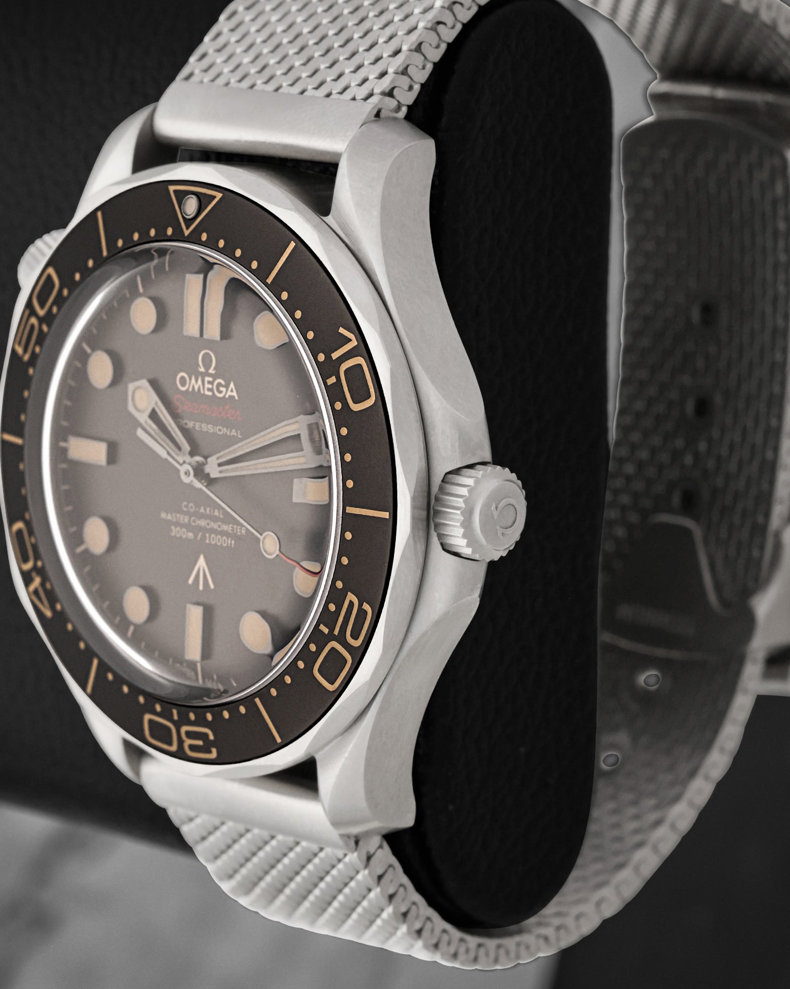 Side profile shot focusing on the brushed titanium case structure, knurled screw-down crown, and scalloped edges of the brown unidirectional bezel