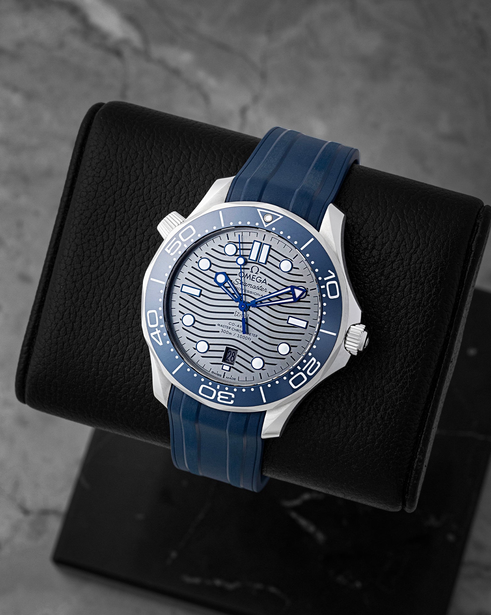 Angled view of 42mm Omega Seamaster Diver 210.32.42.20.06.001 showing chrome laser-engraved wave dial and blue ceramic bezel