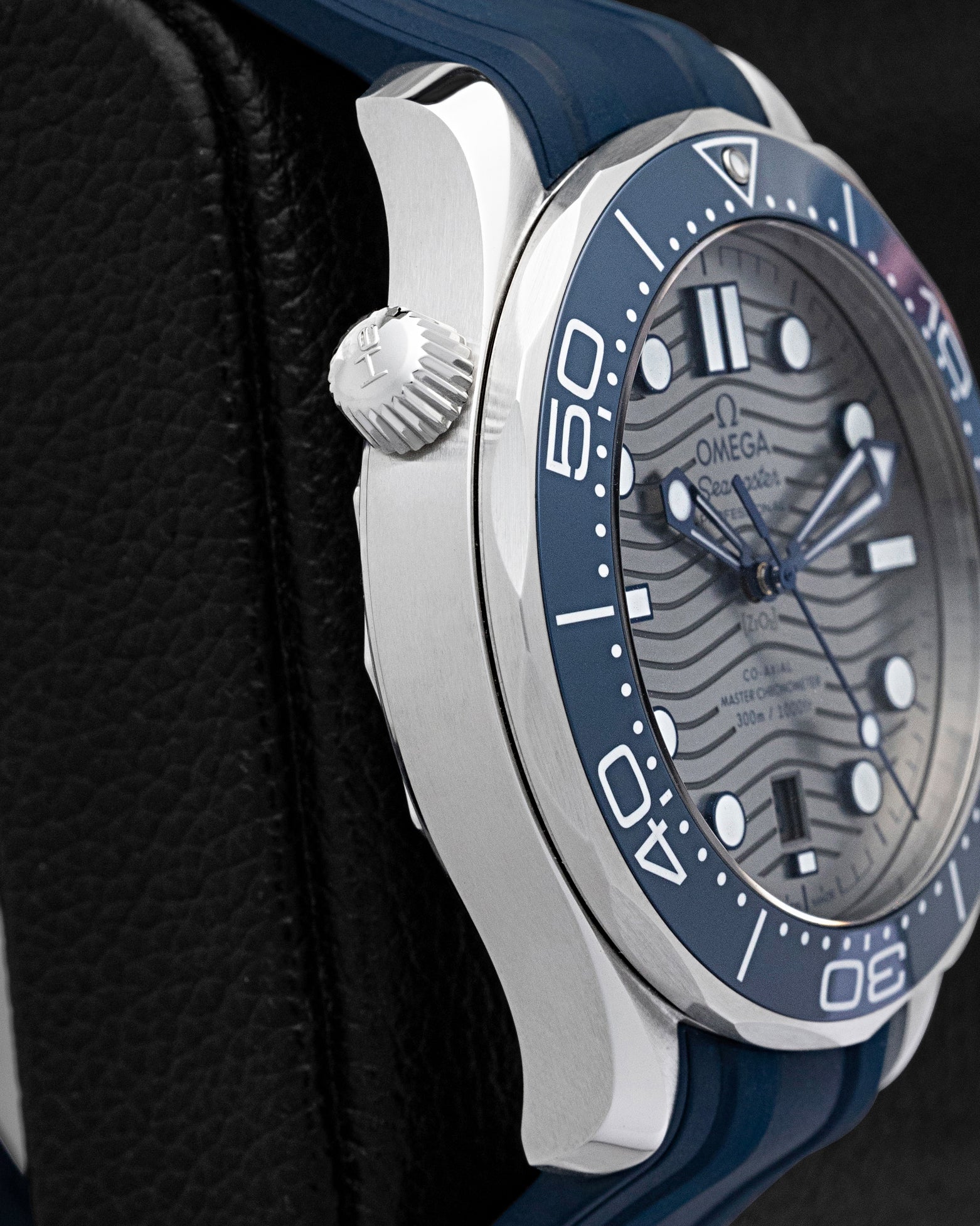 Stainless steel case profile showing blue ceramic bezel edge and Omega logo screw-down crown on reference 210.32.42.20.06.001