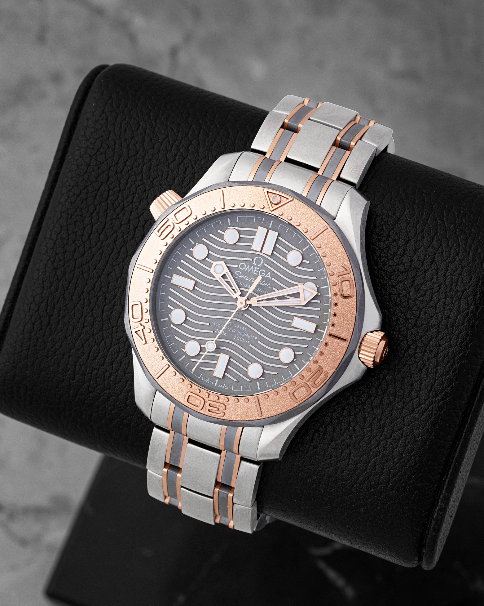 Angled view of Omega Seamaster 210.60.42.20.99.001 showing grey laser-engraved wave dial and 18k Sedna gold bezel