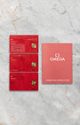 The official red Omega pictogram, master chronometer, and international warranty cards alongside the user instruction guide at Noahs Fine Watches and Jewelry Dallas