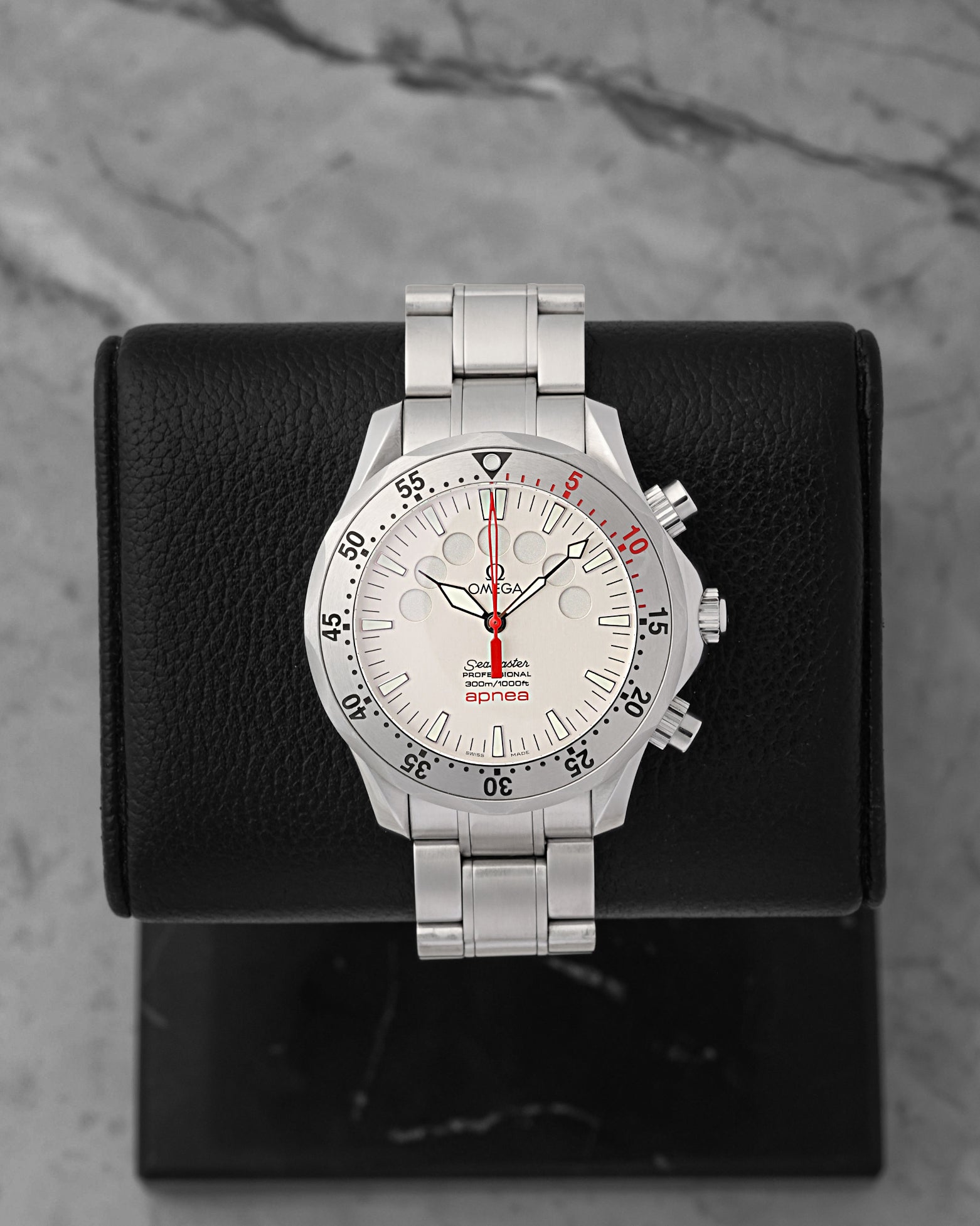 An Omega Seamaster Apnea Jacques Mayol reference 2595.30.00 displaying its silver dial with seven circular free-diving minute timing apertures and a red chronograph hand at Noah's Fine Watches & Jewelry in Dallas