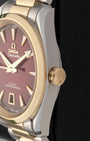 Close-up right profile view of the watch head focusing on the polished 18k Moonshine gold bezel ring and the conical screw-in winding crown embossed with the Omega logo
