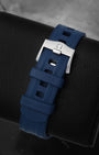 Close-up of the integrated blue structured rubber watch strap and engraved stainless steel pin tang buckle for an Omega Seamaster