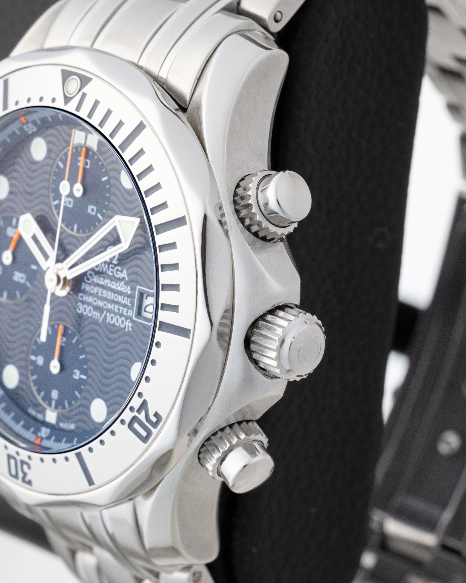 Side profile view of the stainless steel case showing the scalloped bezel, main crown, and screw-down chronograph pushers