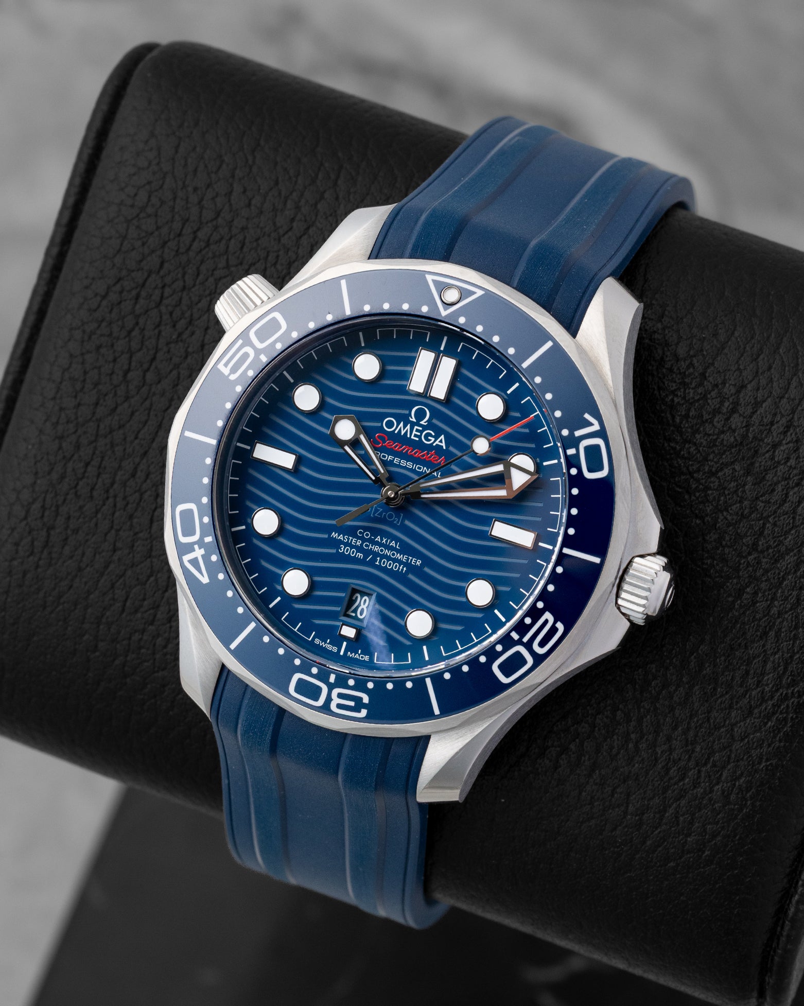 Angled view of a 2024 Omega Seamaster Diver 300M Co-Axial Master Chronometer 42mm watch on a matching blue rubber strap.