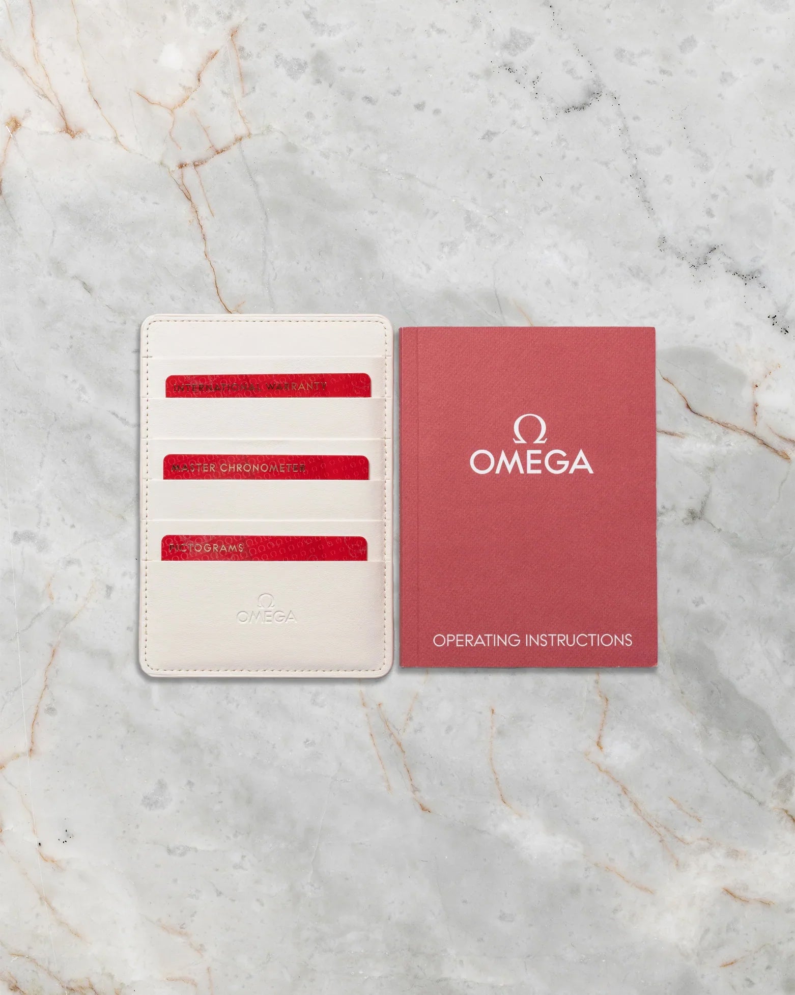 Original Omega red user manual alongside Master Chronometer, Pictogram, and International Warranty cards for the 2022 Seamaster 300M.