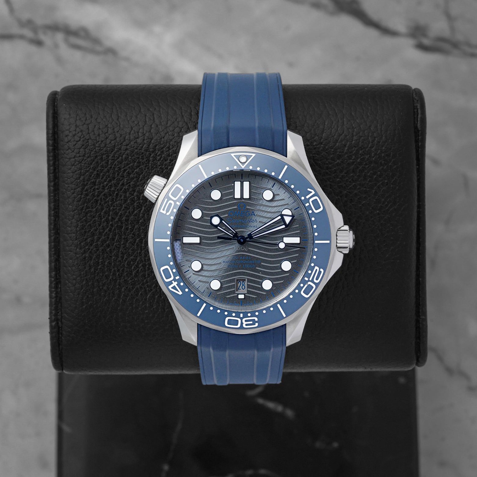 Omega Seamaster Diver 300M Co-Axial Master Chronometer 42mm watch with a grey wave dial and blue rubber strap, model 210.32.42.20.06.001, on display at Noah's Fine Watches & Jewelry in Dallas