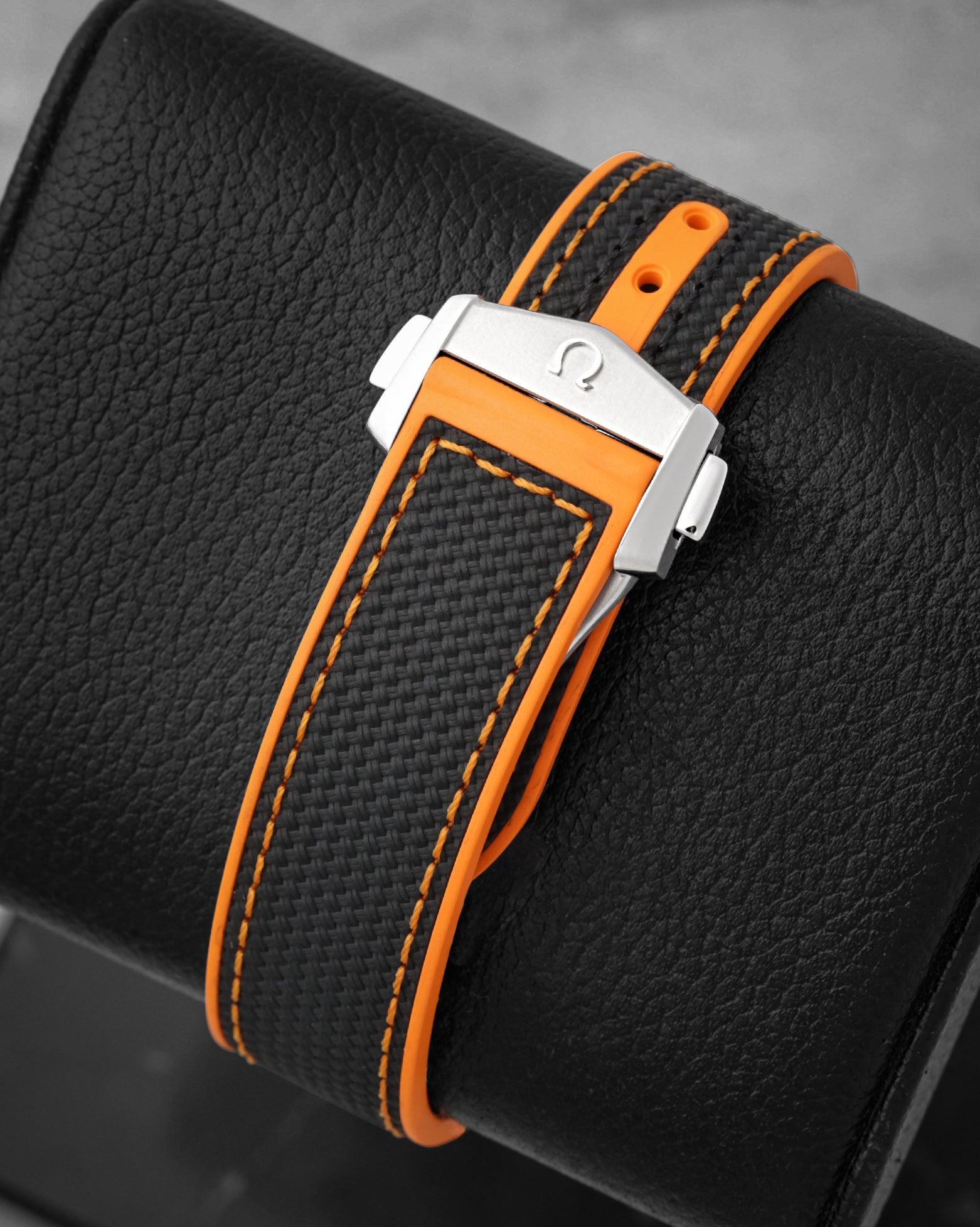 Black structured rubber strap with orange stitching and stainless steel double push-button deployant clasp
