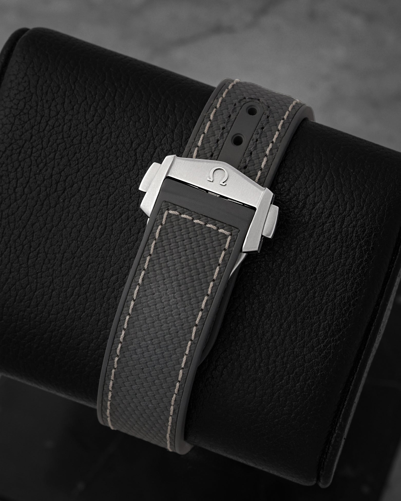 Integrated dark grey rubber strap with folding clasp engraved with the Omega logo