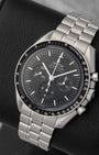 portrait of the 42mm stainless steel Moonwatch case showcasing its black anodized aluminum tachymeter bezel with the historic dot over ninety marker