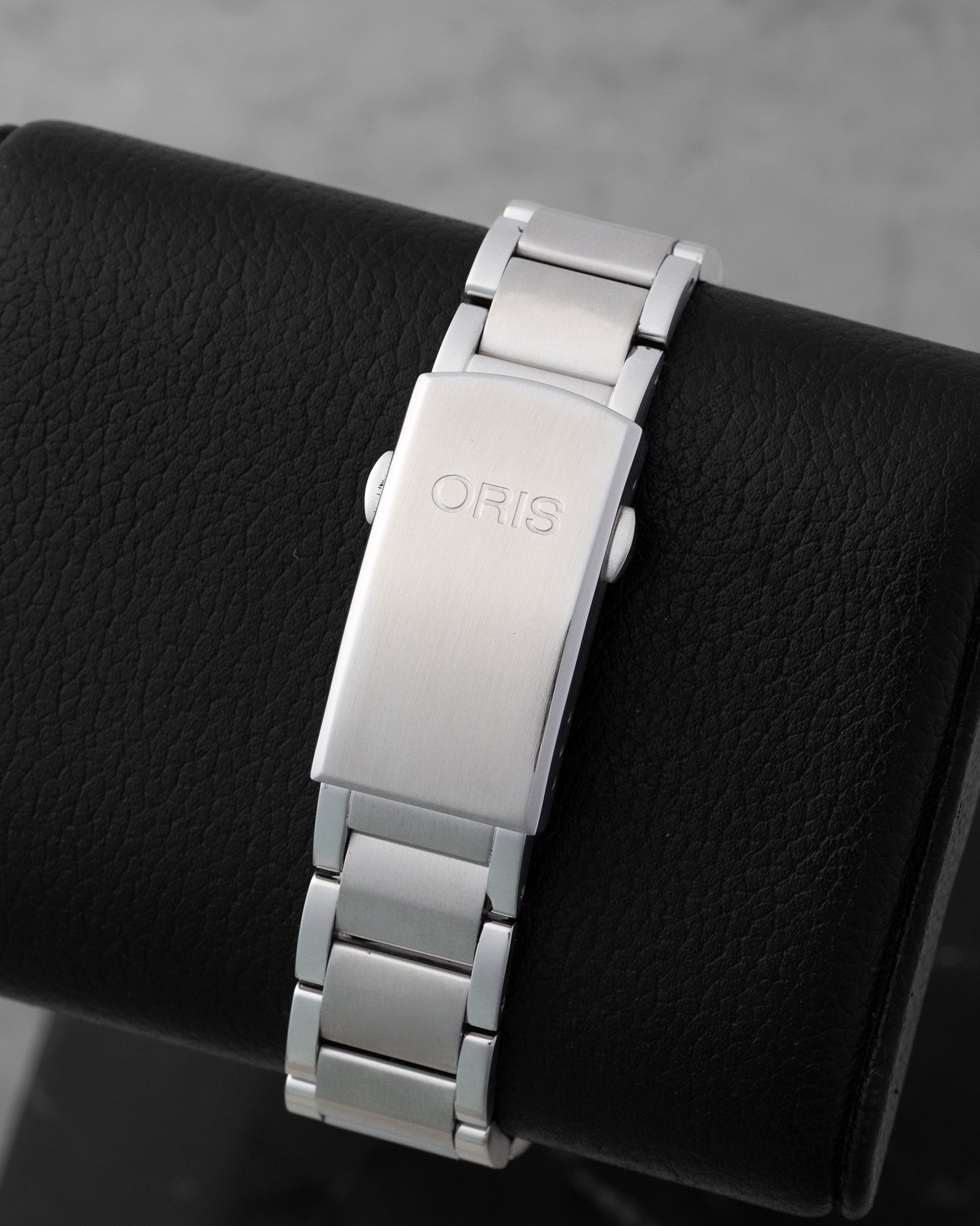 Stainless steel folding security clasp with extension on a black display pillow for the pre-owned 2022 Oris Clean Ocean 01 733 7732 4185.