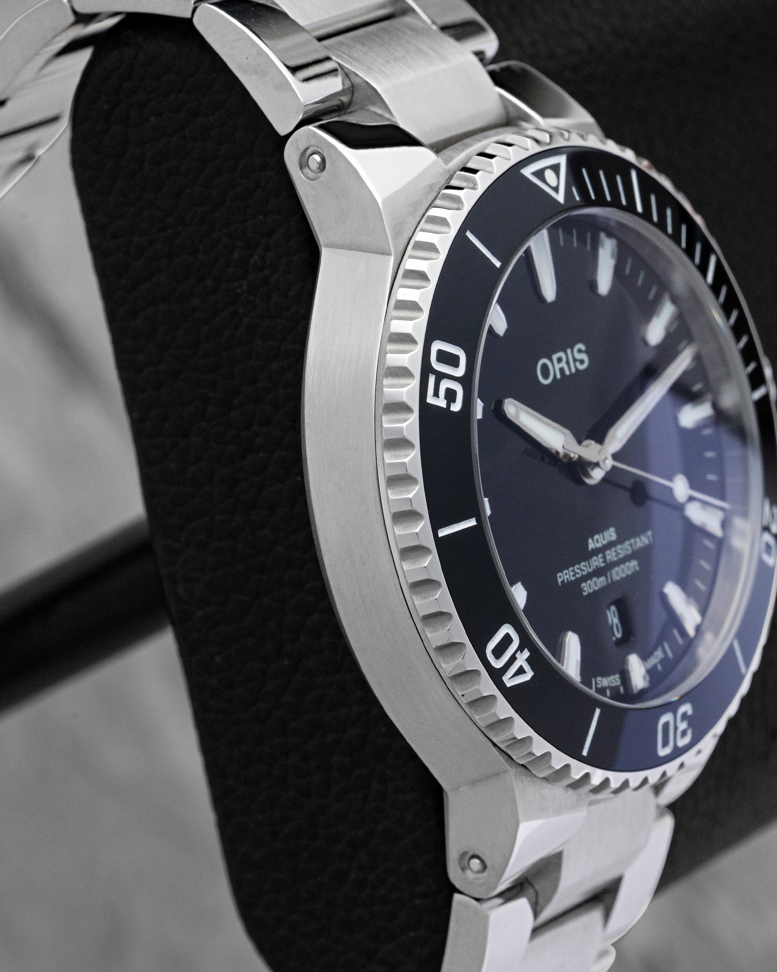Polished stainless steel case profile and black ceramic bezel view of pre owned Oris Aquis Date