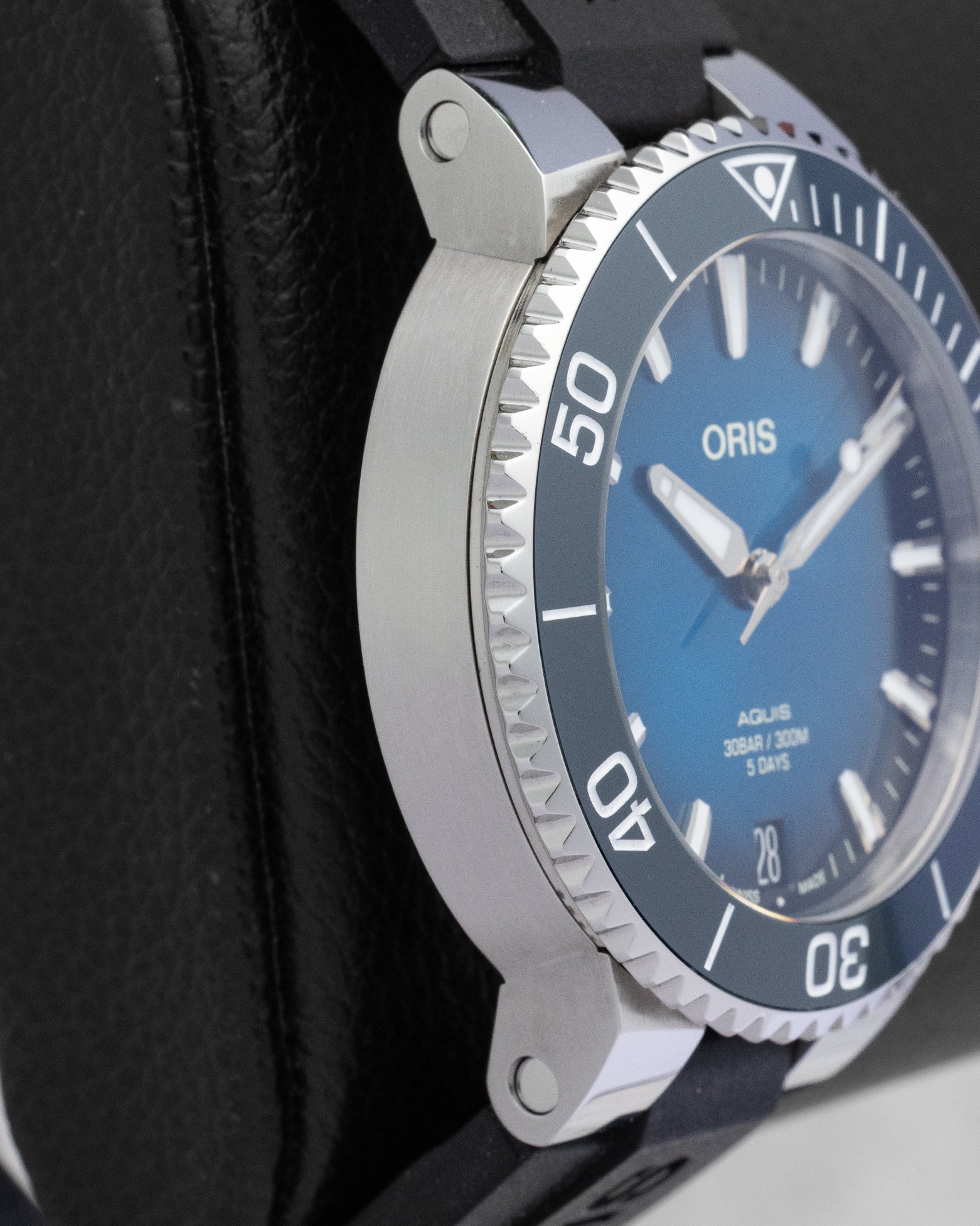 Left profile view of the satin-brushed watch case lugs and the polished knurled edge of a blue Oris diver bezel