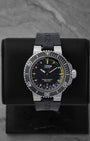 Pre-owned Oris Aquis Depth Gauge reference 01 733 7675 4154 featuring a black dial with yellow gauge channel scale and black rubber strap on display stand.