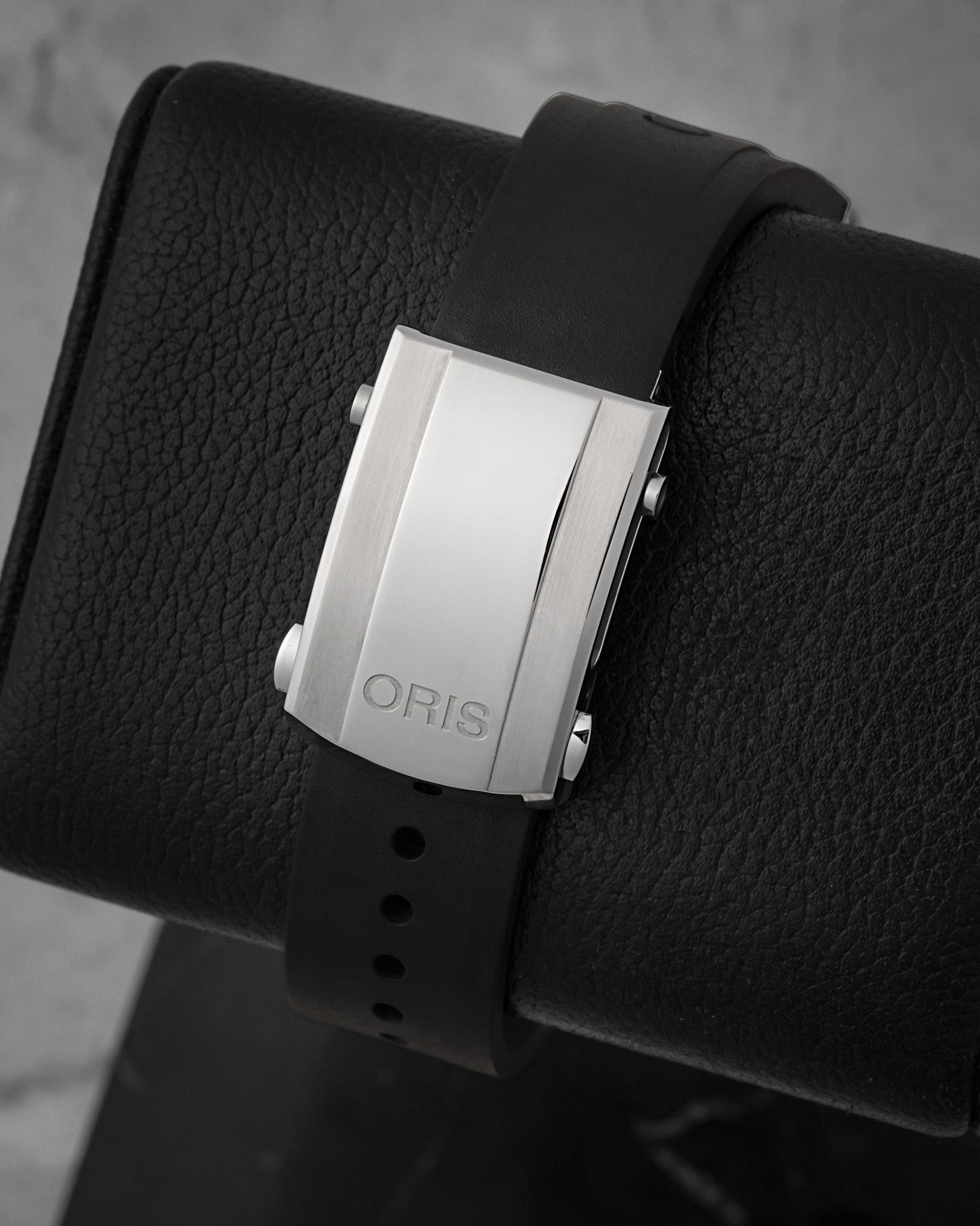 Rear perspective of the black rubber diving strap featuring the Oris text branding and the adjustable stainless steel security folding clasp